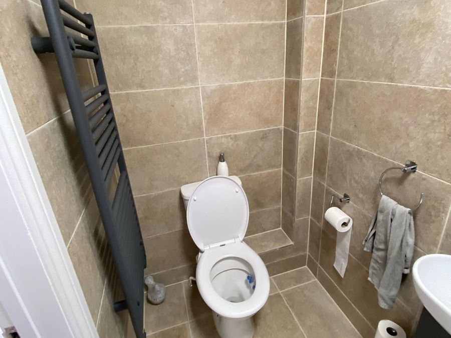 An anthracite towel radiator Jaden fitted in a stone-effect tiled shower room